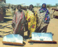 three refugee women proudly display their solar cookers.